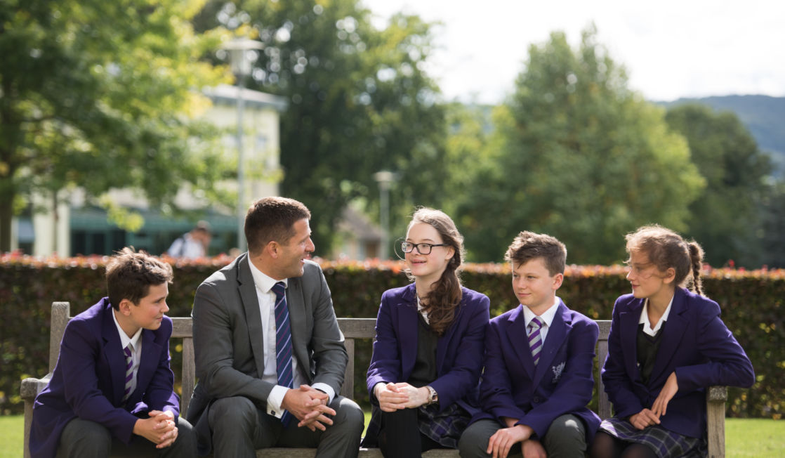 wycliffe kids and teacher sitting on a bench outdoors