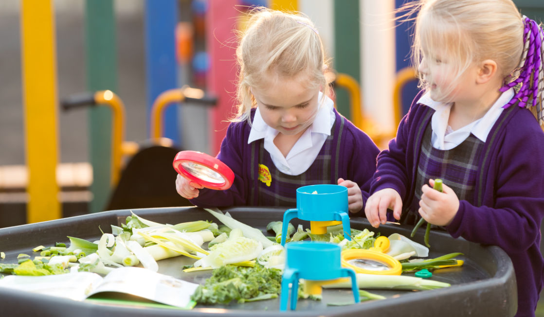 wycliffe nursery girls playing with a magnifying glass