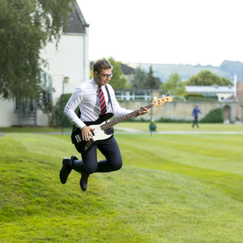 wycliffe student playing the guitar while jumping