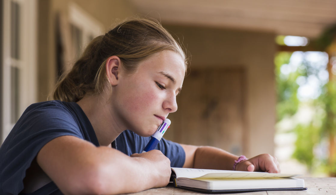 13 year old girl reading and writing in her diary