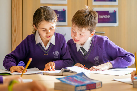 two wycliffe students reading a book in class