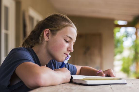 13 year old girl reading and writing in her diary